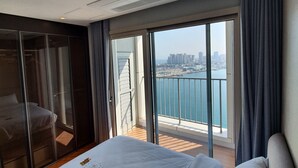 Une chambre d’hôtel avec un grand lit et une porte-fenêtre coulissante donnant sur un balcon avec vue sur la ville.