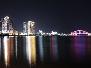 A nighttime cityscape with illuminated buildings and a bridge reflecting on the water. - SOTA SUITE SOKCHO WORLDSTATE (Sokcho)