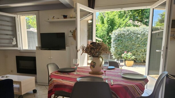 An open-plan living and dining area with a TV, dining table set for two, and a view of the garden.