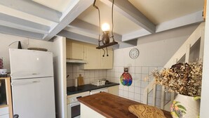 A kitchen with a white refrigerator, wooden countertop, and a clock on the wall.