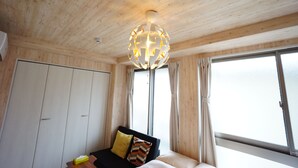 Une pièce avec un plafond en bois, un lit avec des oreillers, une table de chevet et une fenêtre avec des rideaux.