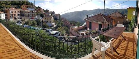 Un barrio residencial con vista a una colina, casas con techos de tejas rojas y coches aparcados.