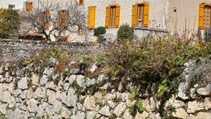A stone building with orange shutters, a rocky hillside, and a clear blue sky. - La Cousteto accommodation in a 17th century fortified house (Roquefixade)