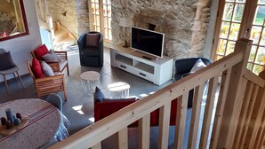 A cozy living area with a TV, seating, and a staircase. - La Cousteto accommodation in a 17th century fortified house (Roquefixade)