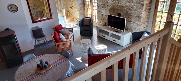 A cozy living area with a TV, seating, and a staircase.