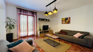 Una sala de estar con un sofá, una mesa de centro, un televisor y una planta.
