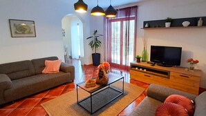 Una sala de estar con un sofá, una mesa de centro, televisor y una planta.