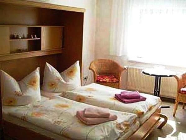 A hotel room with two beds, a chair, a small table, and a window. - FW Herve, MonicaGM 69206-FW Herve, Monica (Graal-Müritz)