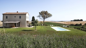 Una casa de dos pisos con piscina, patio y vista al campo.