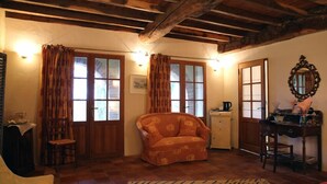 A cozy room with wooden beams, a sofa, a small table, and a chair. - Le Pigeonnier de Guerre (L'Isle-Jourdain)