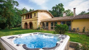A hot tub in a backyard with a house in the background. - Le Pigeonnier de Guerre (L'Isle-Jourdain)