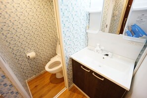 A bathroom with a toilet, a sink, and a mirror. - Terry's Apartment Namba South VI AD05A (Osaka)