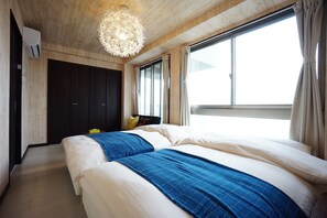 A bedroom with two beds, a wooden ceiling, a large window, and a hanging light fixture. - Terry's Apartment Namba South VI AD05A (Osaka)