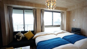 Habitación de hotel con una cama grande, un sofá, un televisor y una ventana con cortinas.