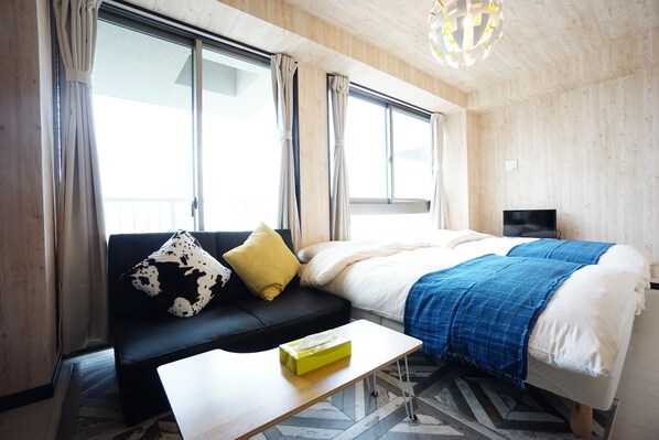 A modern hotel room with a bed, a sofa, a television, and a window with curtains. - Terry's Apartment Namba South VI AD06A (Osaka)
