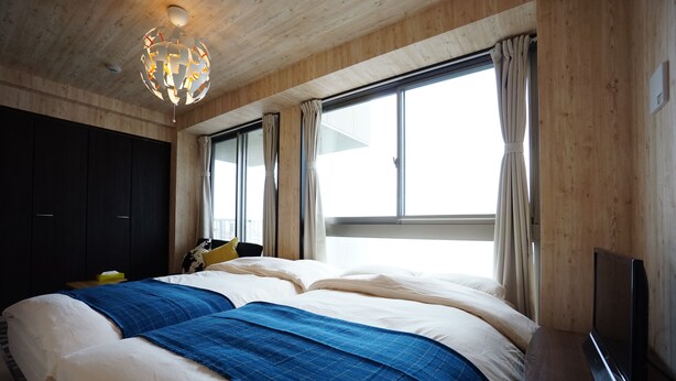Un dormitorio con una cama grande, un televisor y una ventana con cortinas.