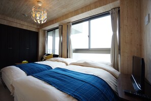 A bedroom with a large bed, a TV, and a window with curtains. - Terry's Apartment Namba South VI AD06A (Osaka)