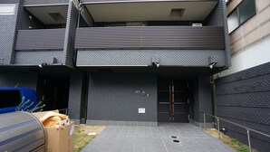 Un edificio moderno con planta baja de baldosas y un balcón con listones horizontales.