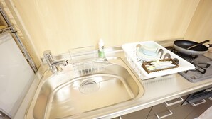 Una cocina con un lavaplatos de acero inoxidable, una encimera blanca y una estufa.