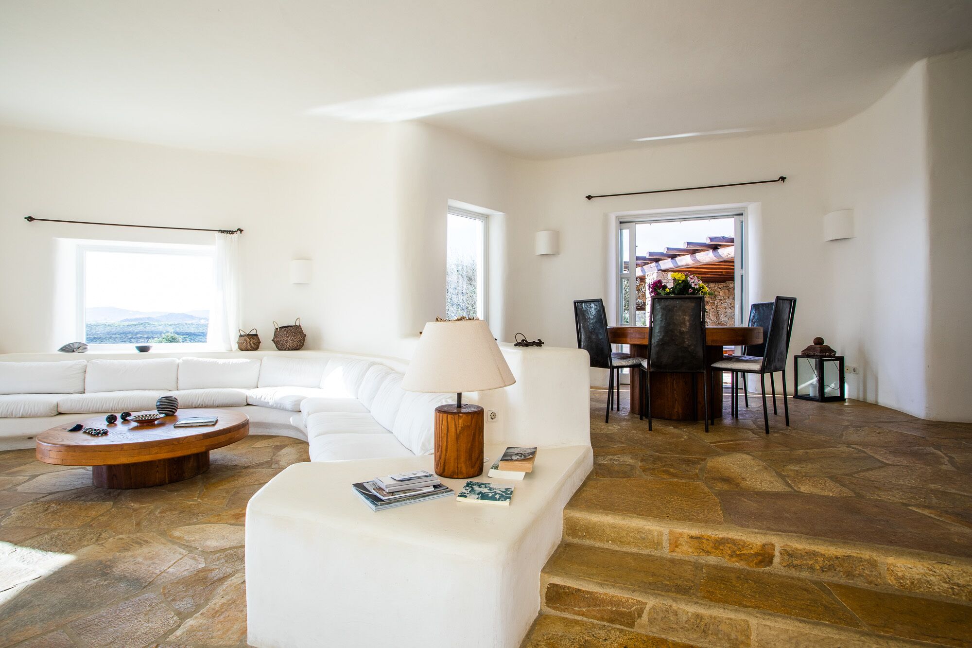 A spacious living room with a white sofa, a coffee table, and a dining area with chairs and a table.