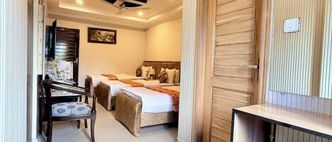 Una habitación de hotel con cama, escritorio, silla, ventilador de techo y puerta.