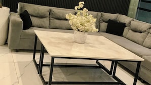 A modern living room with a sectional sofa, a coffee table, and a potted plant. - Hotel Islamabad Premiere Inn (Islamabad)