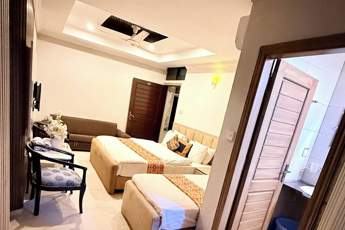 A hotel room with a bed, a sofa, a small table, and a chair.