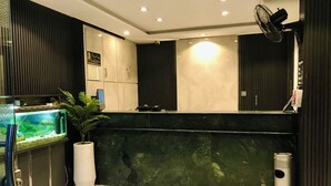 A reception area with a fish tank, a potted plant, a trash can, and a wall-mounted fan. - Hotel Islamabad Premiere Inn (Islamabad)