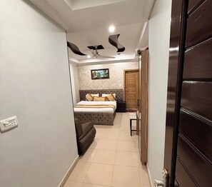 A narrow hallway leading to a bedroom with a bed, a nightstand, and a wooden door. - Hotel Islamabad Premiere Inn (Islamabad)
