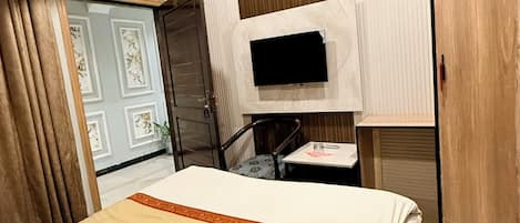 Een hotelkamer met een bed, een aan de muur bevestigde televisie, een bureau en een kledingkast.