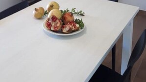 Ruokailutila, jossa on valkoinen pöytä ja lautasellinen ruokaa. Taustalla näkyy metallikaiteella varustettu portaikko.