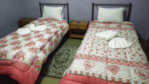 Two single beds with floral bedding, wooden nightstands, and a patterned rug. - Pinguino Hostel Athens (Athens)