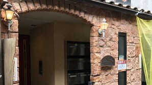 A building entrance with a stone facade, a metal door, and a mailbox. - Terry's Apartment Shinsaibashi I M04B (Osaka)