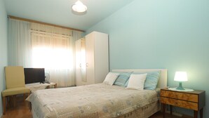 A bedroom with a bed, a television, a desk, a wardrobe, and a nightstand with a lamp. - Apartment 1995/28135 (Istria - Pula), 750m from the beach (Pula)