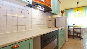 A kitchen with light green cabinets, a white refrigerator, and a tiled backsplash. - Apartment 1995/28135 (Istria - Pula), 750m from the beach (Pula)