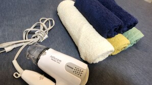 A hairdryer, a pair of white earphones, and a set of towels on a grey surface. - Smart Stay Tokyo L333 (Tokyo)