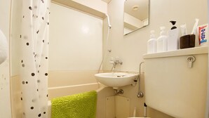 A bathroom with a white sink, a green towel, and toiletries on a shelf. - Smart Stay Tokyo L333 (Tokyo)