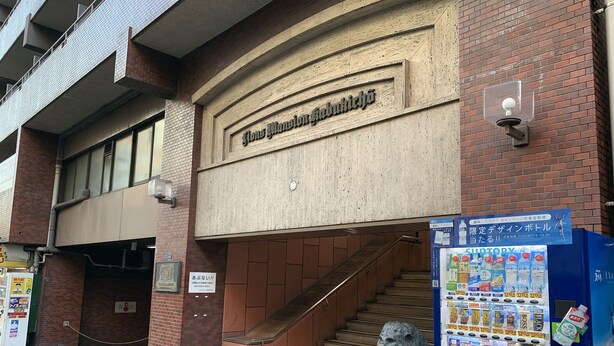 A building entrance with a staircase, a vending machine, and a statue of a lion. - Smart Stay Tokyo L333 (Tokyo)
