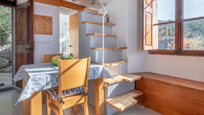 Een houten interieur met een tafel en stoelen, een raam met uitzicht en een trap.