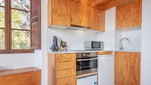 Een compacte keuken met houten kastjes, een magnetron, een vaatwasser en een inbouwoven.