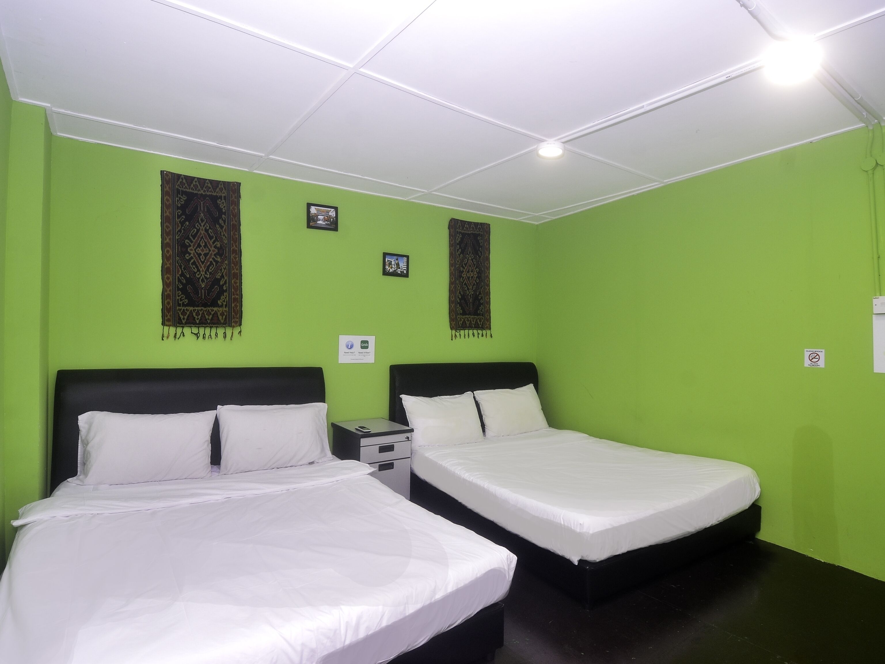A room with two beds, green walls, and a white ceiling.