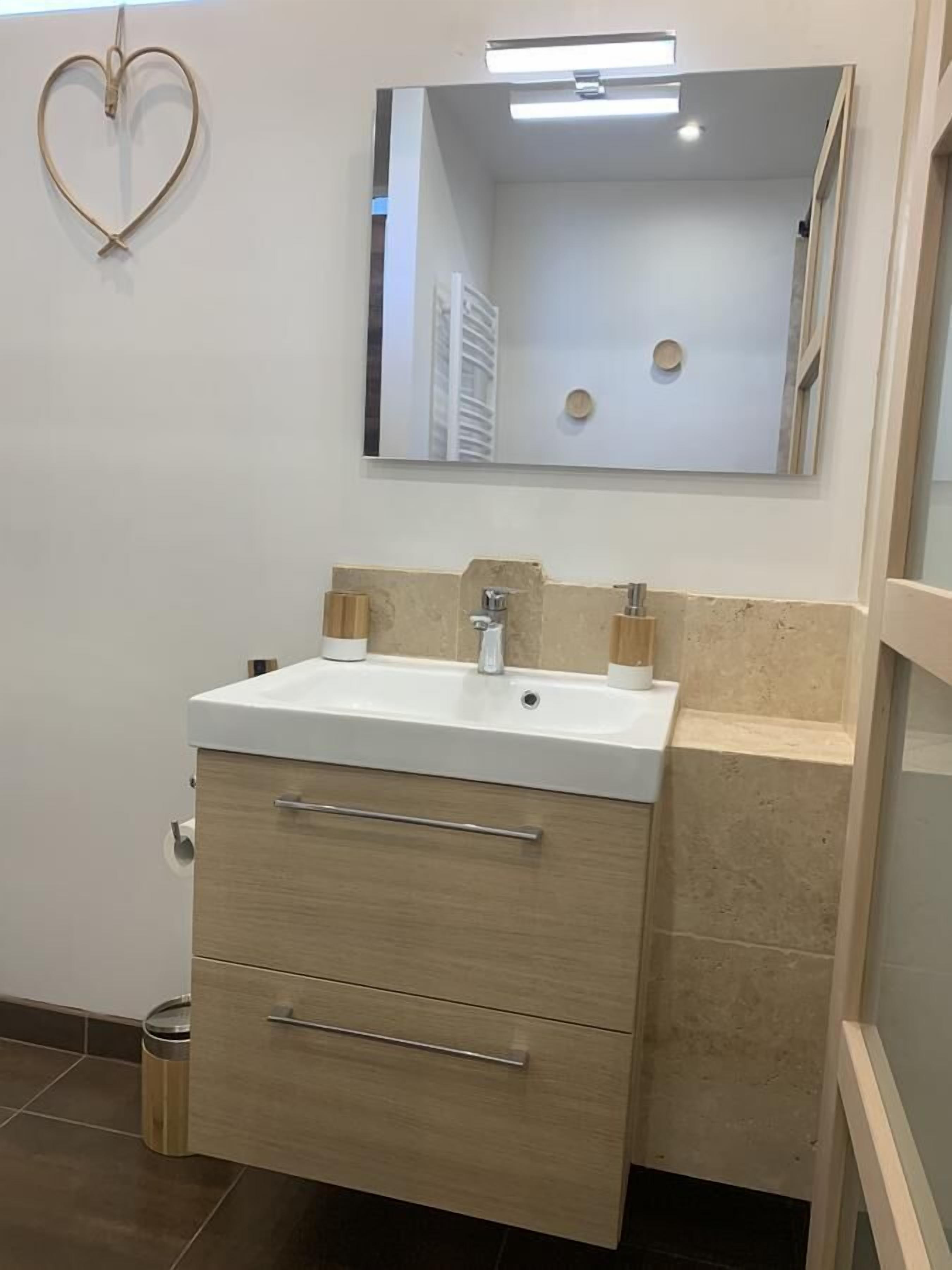 Ein Badezimmer mit einem weißen Waschbecken, zwei Spiegeln und einer Holzausstattung.