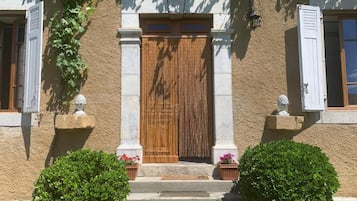 A building with a wooden door, white shutters, and a stone facade.