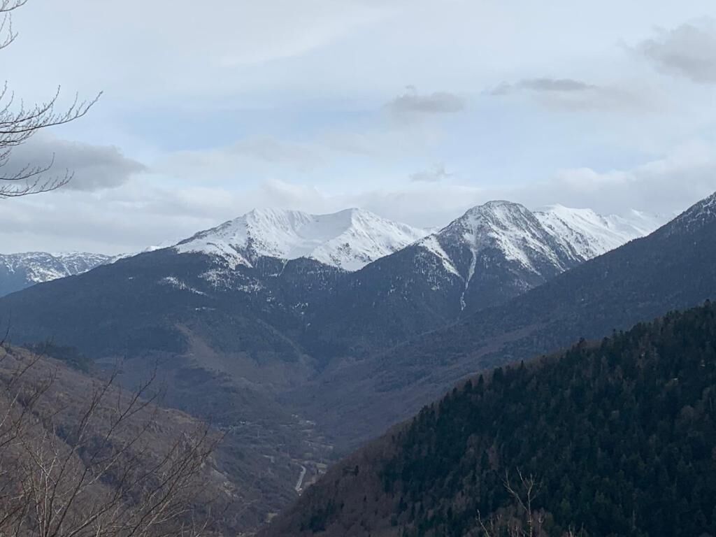 Un paysage montagneux avec des sommets enneigés et une vallée.