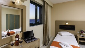 Ein Hotelzimmer mit Bett, Schreibtisch, Laptop, einer Weinflasche und Gläsern.