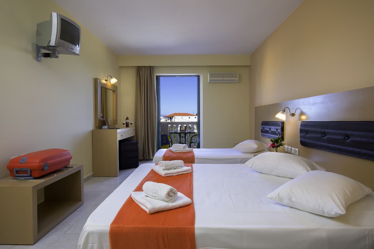A hotel room with two beds, a desk, a TV, and a window with a view.