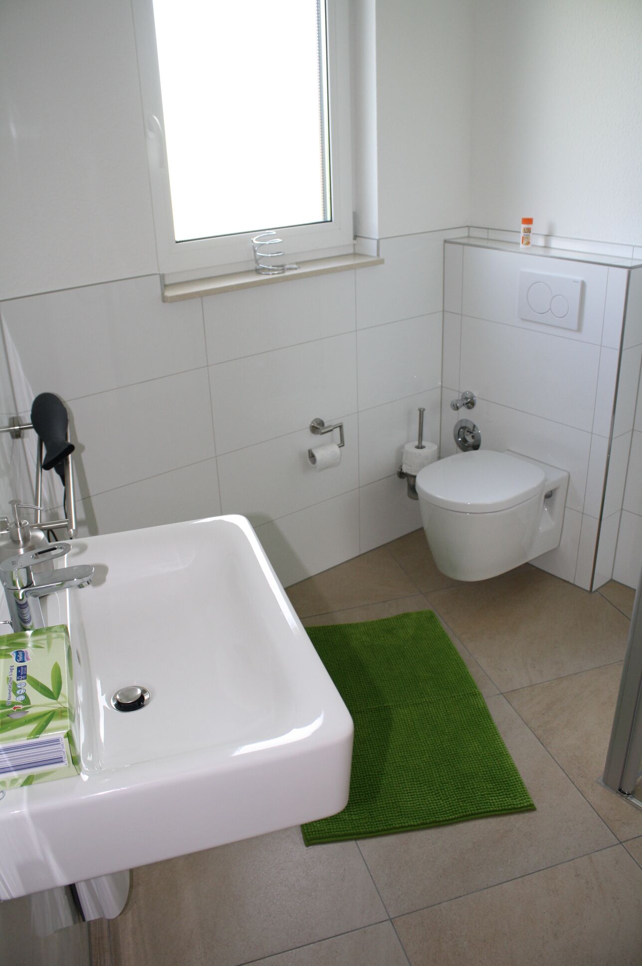 Un baño con un lavabo blanco, inodoro y una alfombra verde.