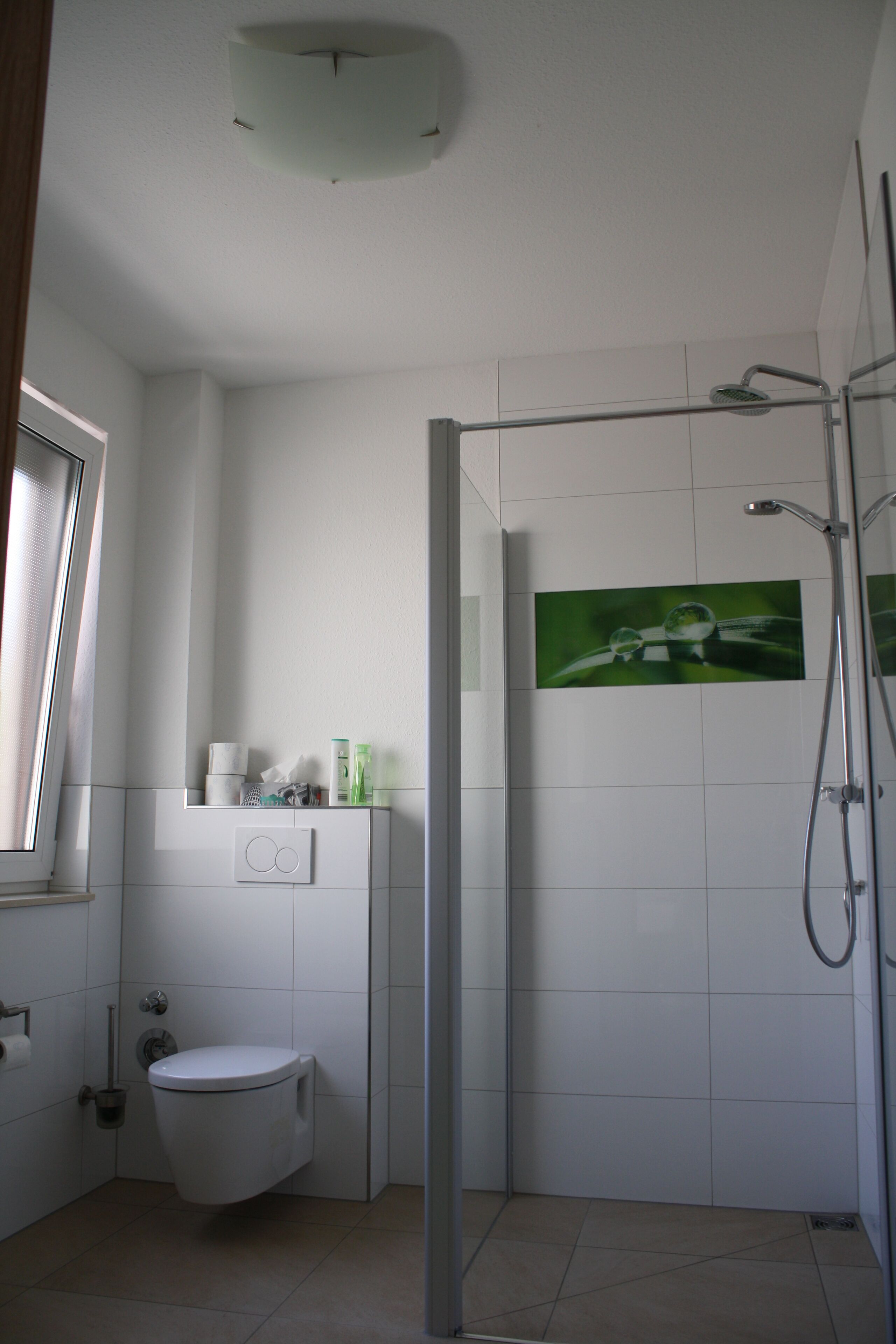 A modern bathroom with a toilet, a shower, and a window.