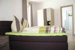 Un dormitorio con cama, armario y espejo.