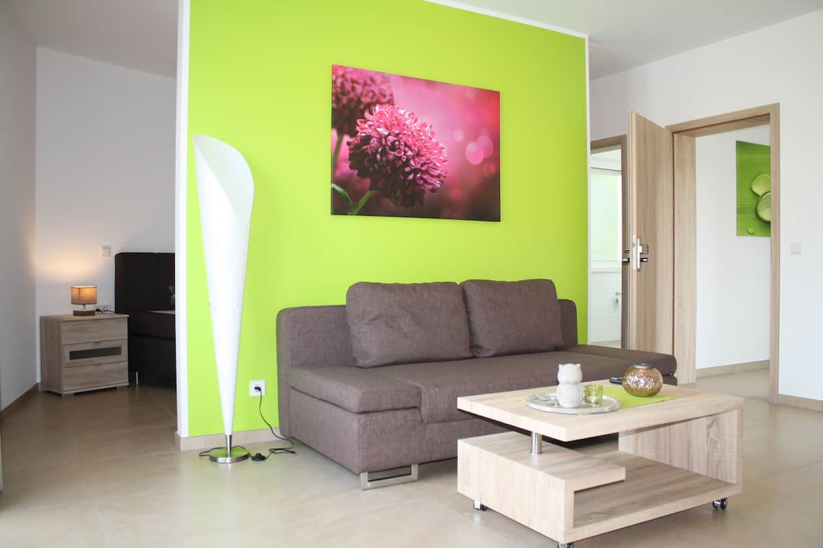 A modern living room with a grey sofa, a wooden coffee table, and a bright green accent wall.